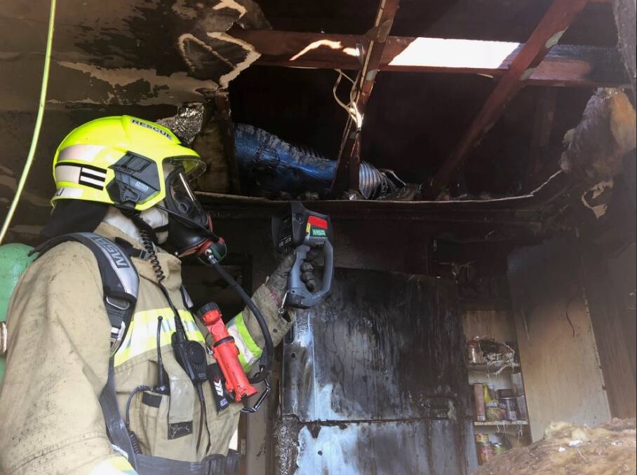 DAMAGE: A firefighter inspects the scene of the fire at the Thurgoona home on Tuesday morning, which caused damage to the kitchen. Picture: Fire and Rescue NSW