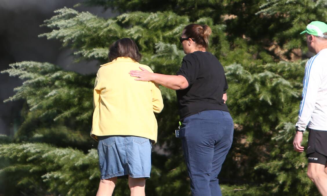 Pam Waldron is comforted by a woman outside the smoking home. Picture by Blair Thomson