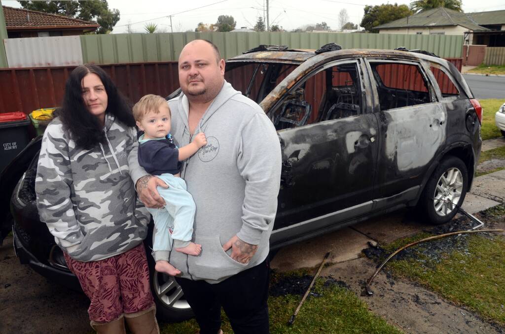 BURNT: Parents Ashley McColl and Brian King with their son Dontae and their destroyed Holden Captiva. The car was set alight 4am on Thursday. Picture: BLAIR THOMSON