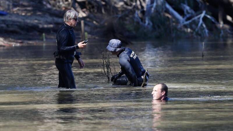 SEARCH: Police divers search the river after the incident. 