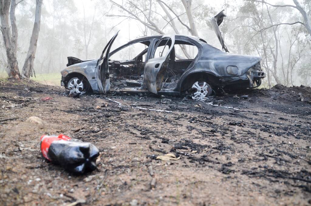 SET ALIGHT: The Ford Falcon was driven up a track on Nail Can Hill in West Albury before being set alight. The occupants fled from the scene. Picture: BLAIR THOMSON