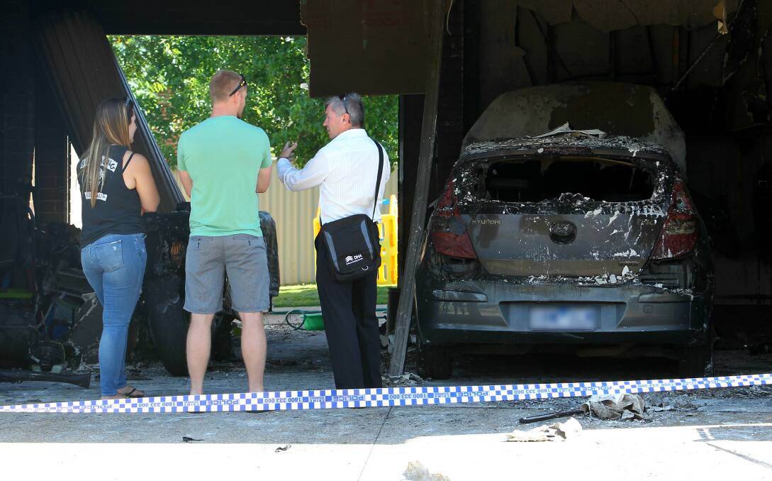 DESTROYED: Jessica and Paul Darcy talk to a Defence Housing Australia worker outside their damaged garage on Friday. Picture: BLAIR THOMSON
