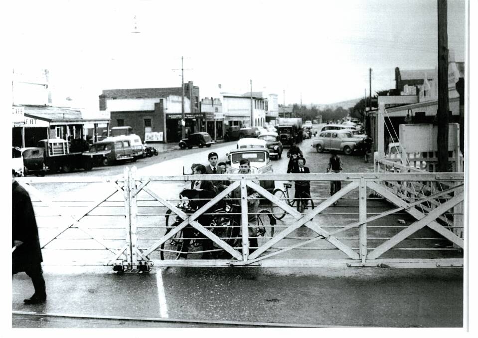 CYCLING FUN: Pictured is the level crossing at 90 High Street, gates closed, with people waiting for the train to pass.