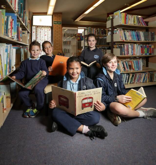 WONDER OF WORDS: Glenroy Public School pupils Jax Murray, 5, Maddison Baker, 5, Ericka Banosia, 8, Emily Oliver, 12, and Daniel Phillips, 12, enjoy their school library. Picture: JAMES WILTSHIRE