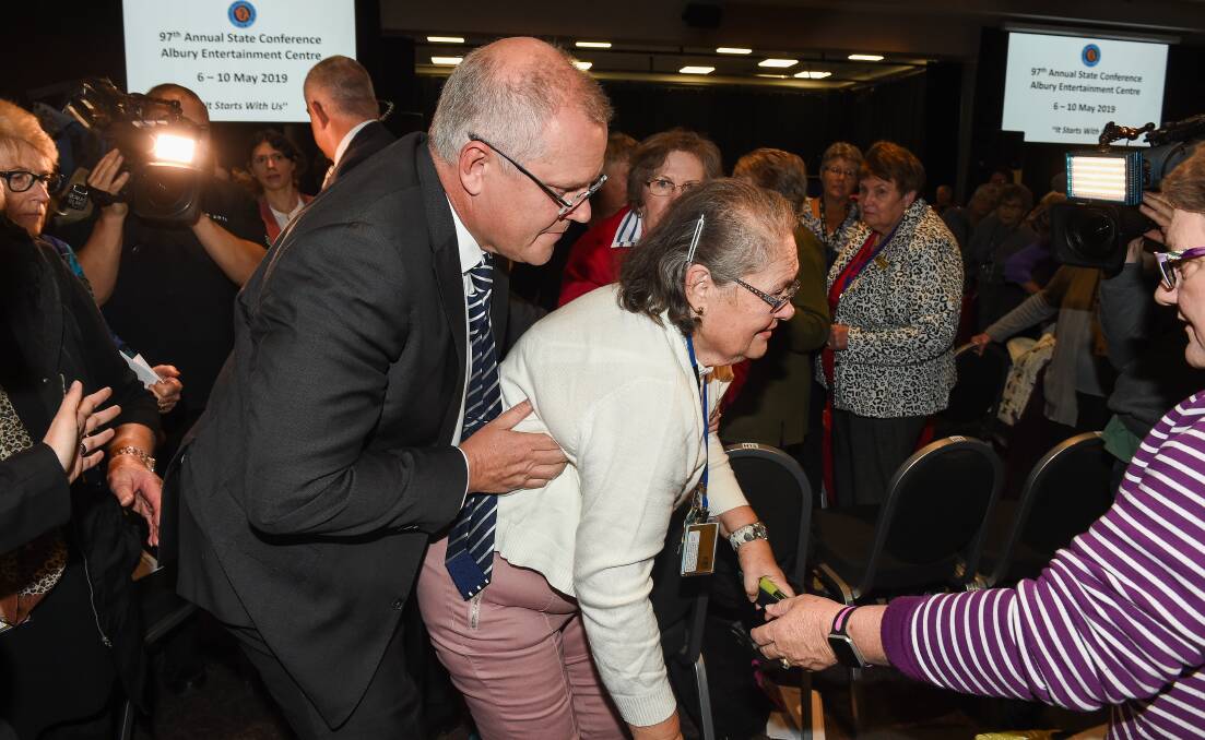 Australian Prime Minister Scott Morrison helps a woman knocked over during the drama caused by Amber Holt's assault on him in Albury on May 7. Picture: MARK JESSER