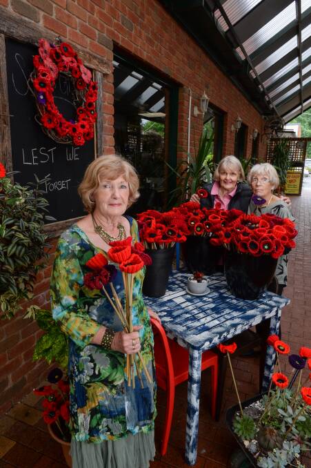 BURSTS OF COLOUR: Mount Beauty line dancers Joy Partington and Robyn Quick and Upper Kiewa Valley Lions Ladies president Pam Casey with some of the 1100 flowers decorating the town. Picture: MARK JESSER