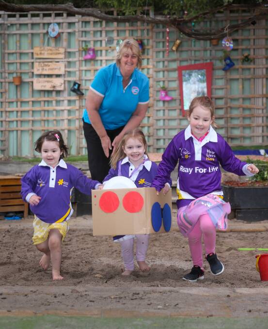 TRAINING RUN: Shelbie Ritchie, 3, Victoria Holmes, 3, and Scarlett Ritchie, 4, try out a decorated box race, watched by Goodstart educator Debbie Reid. Picture: KYLIE ESLER