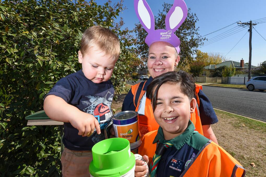 APPEALING: Hudson Hill, 2, donates to collectors Katie Mott and Henry Mott, 11, of the 1st Wodonga Scouts, during the Border's Good Friday Appeal. Picture: MARK JESSER