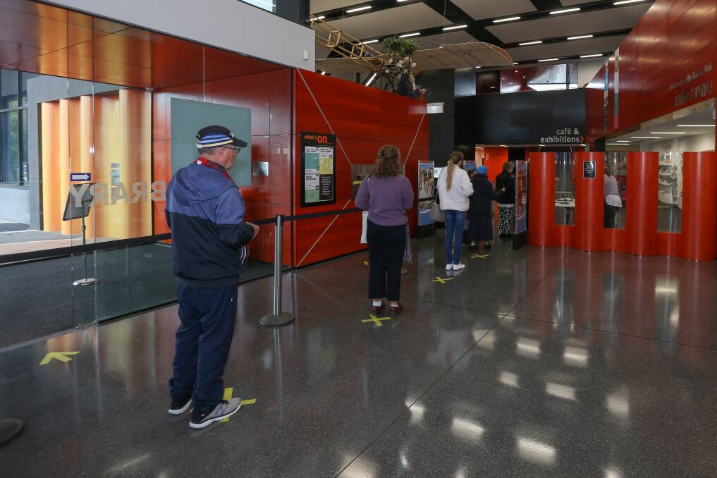 NEW ROUTINE: Patrons stand in the Albury Library Museum foyer, waiting to sanitise their hands and provide contact details before entering the main space. Picture: TARA TREWHELLA