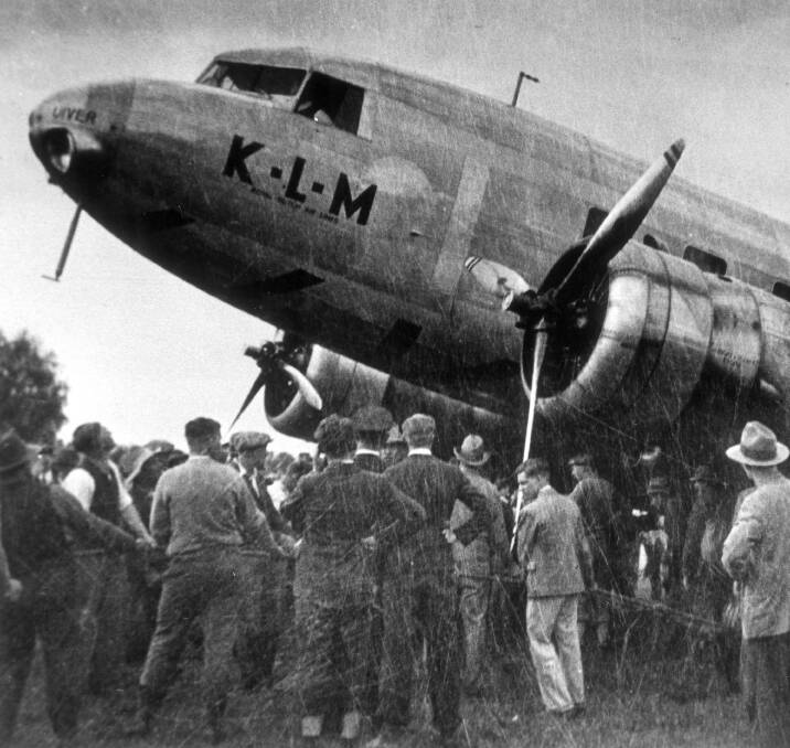 TEAM WORK: After using car headlights to guide the Uiver safely down a makeshift runway at Albury racecourse overnight, Albury residents help to pull the bogged Dutch airliner out of the mud in the morning of October 24, 1934.