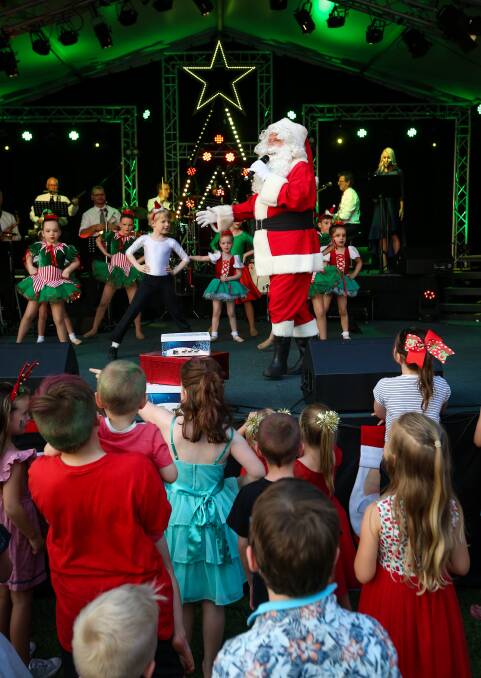 FAMILIAR FIGURE: Children crowd the stage when Santa Claus makes his appearance. He and the dancers present two numbers, Go Santa Go and Aussie Jingle Bells. Picture: JAMES WILTSHIRE