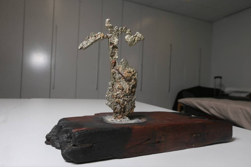 SYMBOLIC: This piece of lead melted into the shape of a cross. It is mounted on burnt timber from St Matthew's. Picture: TARA TREWHELLA