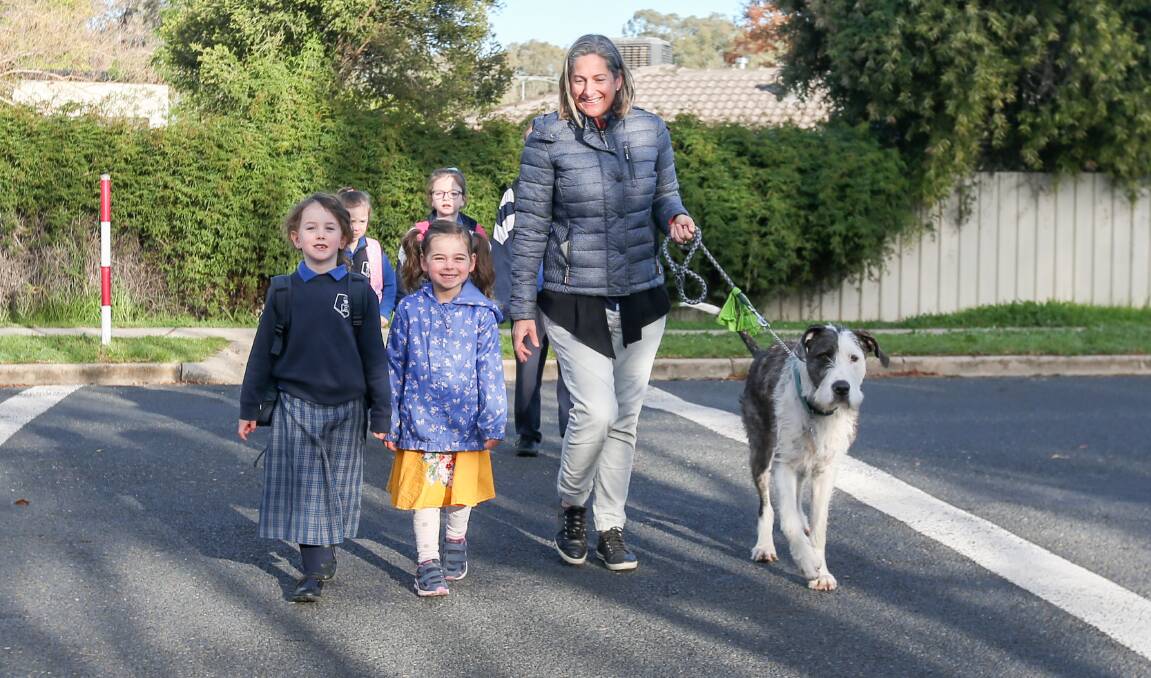GLAD TO BE BACK: Abby-Mae Collis, 6, crosses the road outside Thurgoona Public School with her sister Isabel, 4 and mother Penny on Monday, ready to resume her first year of school. Picture: TARA TREWHELLA