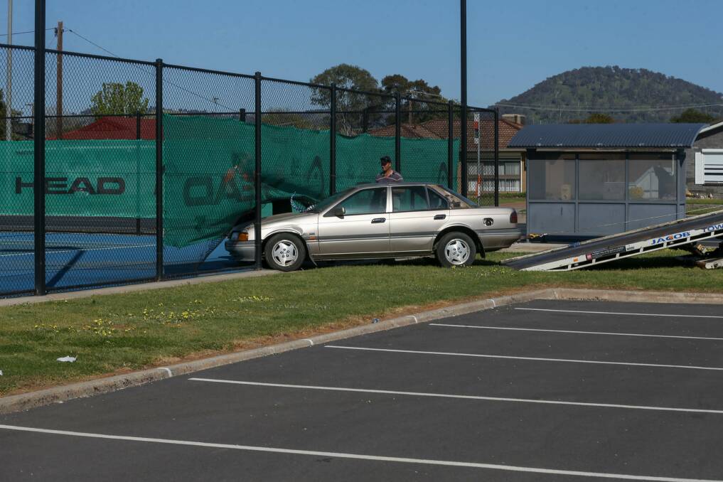 MOPPING UP: The Ford Falcon is towed out of Wodonga Tennis Centre on Tuesday morning, leaving behind a damaged fence and tyre marks on the court. Picture: TARA TREWHELLA