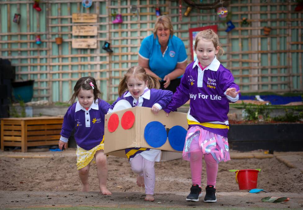 TRAINING RUN: Shelbie Ritchie, 3, Victoria Holmes, 3, and Scarlett Ritchie, 4, try out a decorated box race, watched by Goodstart educator Debbie Reid. Picture: KYLIE ESLER