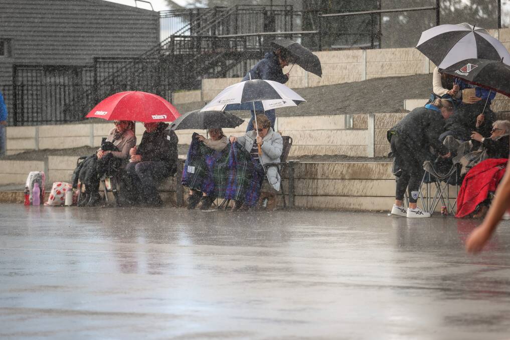 WINTER WEATHER: Spectators huddle under umbrellas as rain falls during Saturday's Ovens and Murray netball match between Wodonga Bulldogs v Corowa Rutherglen. Picture: JAMES WILTSHIRE