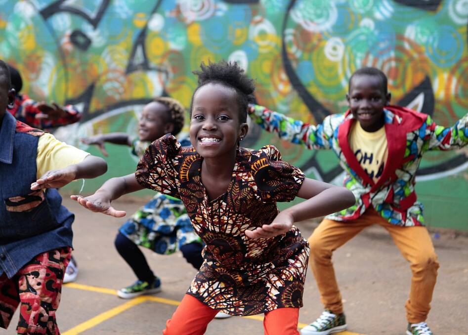 FULL OF JOY: Priscilla Mirembe dances with her fellow Watoto Children's Choir members. The group will perform in Albury on Thursday evening.