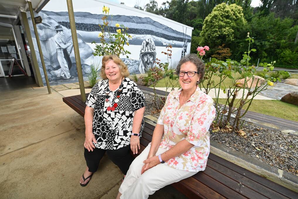 FAMILIAR FACES: Lesley Barlee and Louise Werrett have lived in Khancoban for years. The mural behind them reflects the town's links to the Snowy Scheme. Picture: MARK JESSER