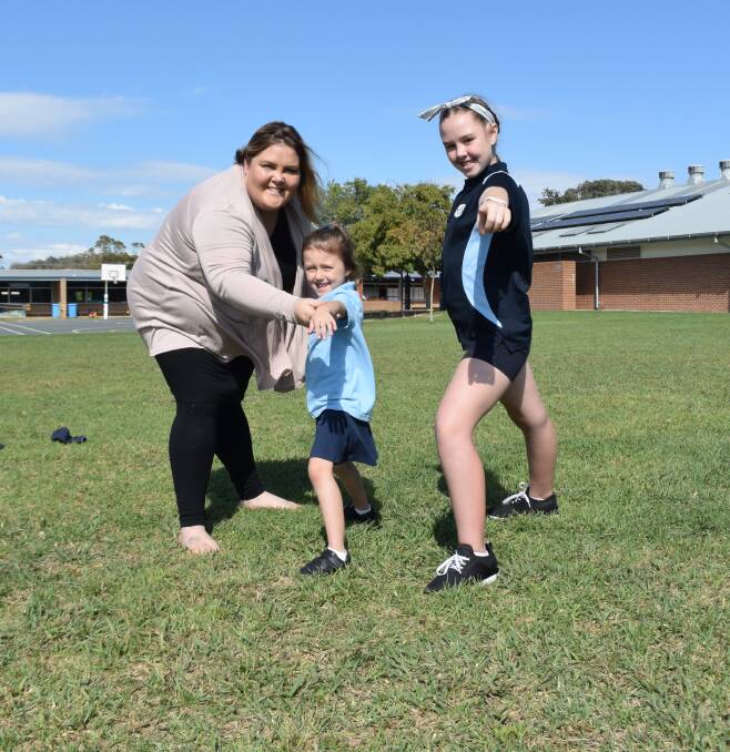 HAVING A GO: Glenroy Public School students Lily Randal, 5, and Miah Fitzpatrick, 11, demonstrate some yoga positions with Mindful Warrior Anna Gannon.