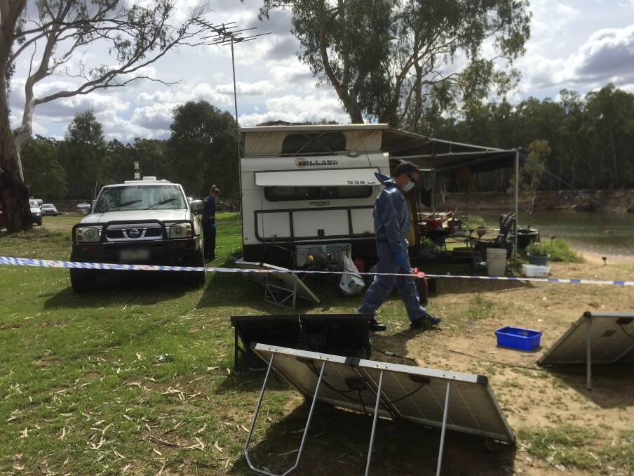 CRIME SCENE: Officers examine the caravan where the injured man lived.