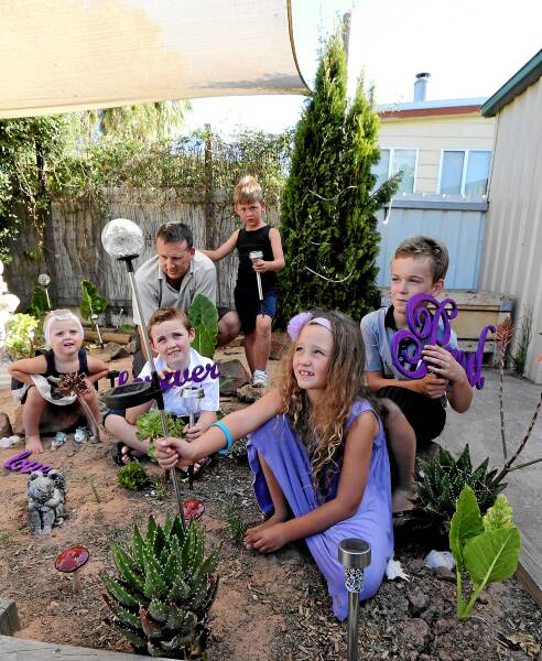 Aaron Taylor and his son Noah, 7, help Tyler, 9, Daytona, 7, Jack, 5, and Shyla Turnbull, 2, decorate the garden Paul Turnbull made before he died. Picture: KYLIE ESLER
