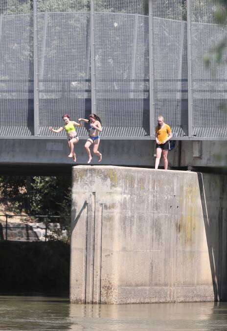 RIGHT: Two girls take a running jump into the Murray River after squeezing past a safety barrier on the Union Bridge. Picture: JOHN RUSSELL