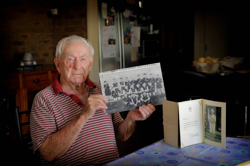 Bill Chisnall celebrated his 100th birthday last week. He is pictured holding a team photo of the Corowa Football Club from about 1933, when he played with his two brothers, and alongside that is a letter he received from the Queen to mark his birthday. Picture: TARA GOONAN