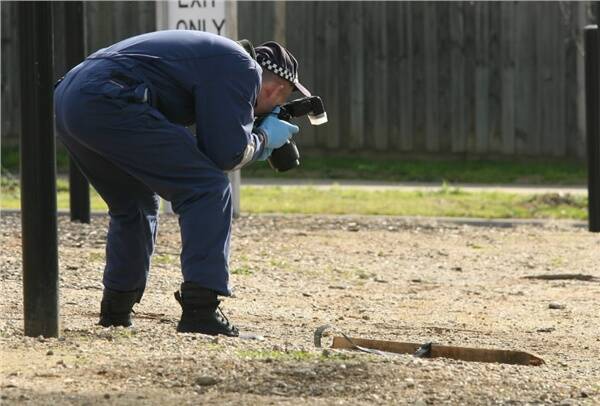 Police forensic photographer takes a photo of a tree stake. One simillar to this was used in the attack on a person that resulted in his death. 