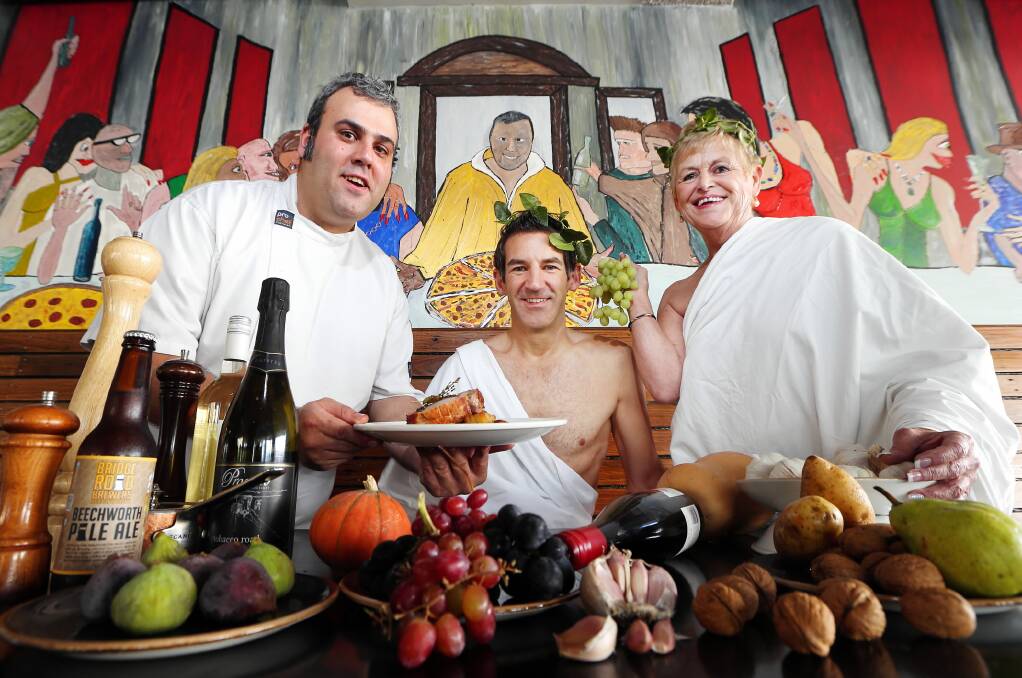Cafe Victor chef Carlos Saliba offers roast pork to Rivalea’s Paul Da Silva and Carevan’s Di Mant ahead of next week’s A Roman Feast to Share event. Picture: John Russell