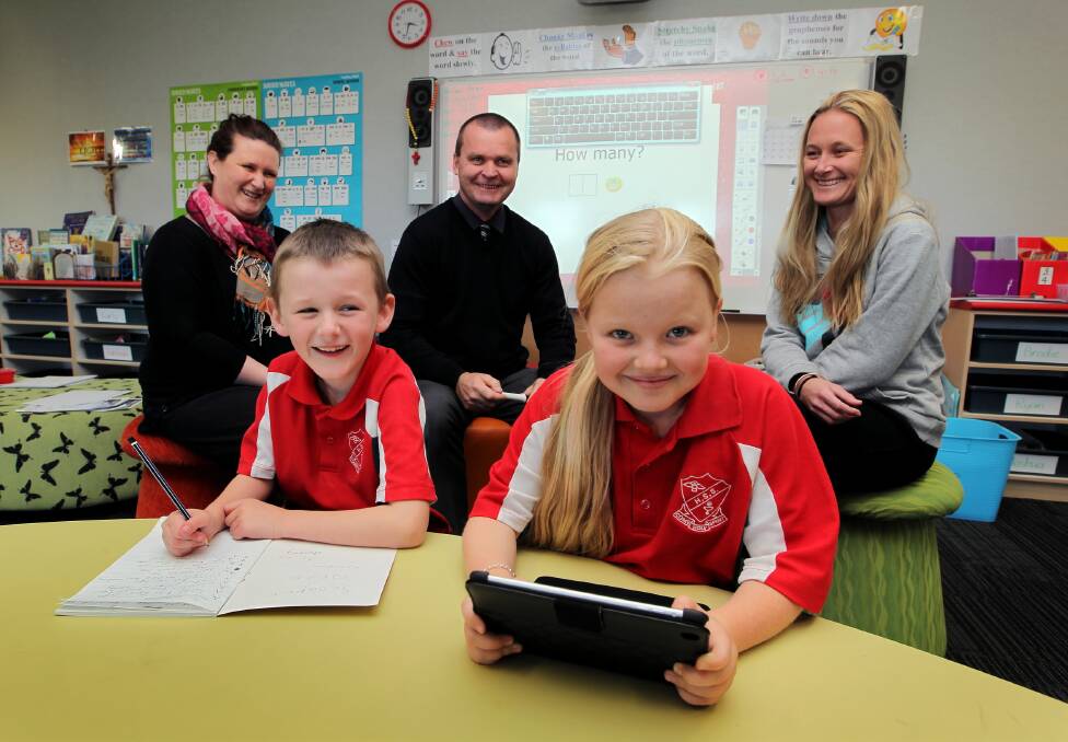 Noah and Charli of Holy Spirit Primary School test their computer and handwriting skills with parents Stacey Condon and Dannii Heriot and principal Mark MacLean looking on. Picture: DAVID THORPE