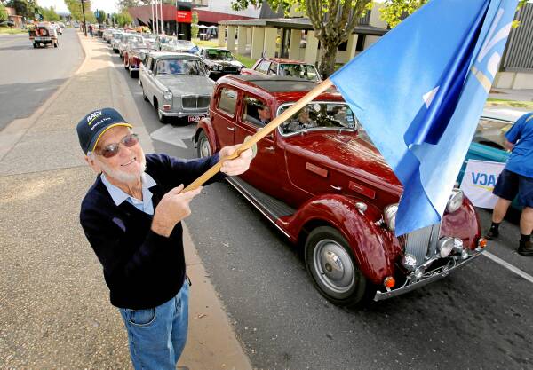 Brian Grealy from Wodonga RACV waves the flag to get the old cars under way. Picture: DAVID THORPE