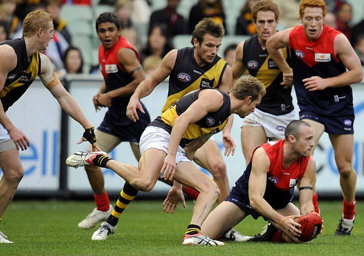 Melbourne's Matthew Warnock grabs the ball as Richmond defender Luke McGuane bears down on him in the round 18 clash in 2009.