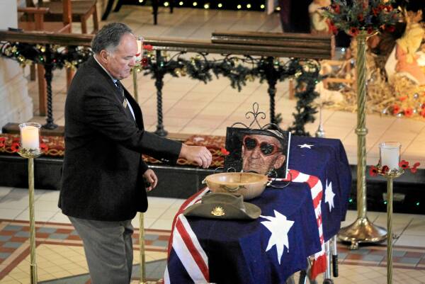 President of the Albury RSL sub-branch Colin Darts places a poppy on the coffin — Anzac Day won’t be the same without Mr Moras leading.