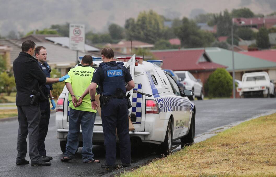 Police take a man into custody from a home in Marshall Street yesterday. Picture: JOHN RUSSELL