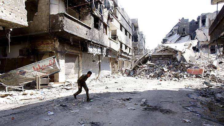 Back in the civil war: A pro-regime fighter takes cover in the Yarmouk refugee camp in Damascus. Photo: AFP/Anwar Amro