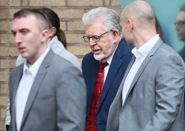 Veteran entertainer Rolf Harris walks with his security guards as he arrives at Southwark Crown Court, in London.