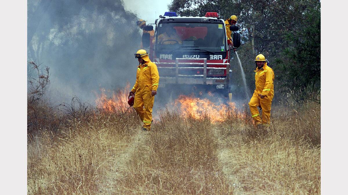 Firemen Wayne Gibbs and Stephen Carroll  burn off the grass while the firemen on the truck keep it under control. They are clearing the old disused railway track running past Bonegilla onto Tallangatta. Picture: PETER MERKESTEYN