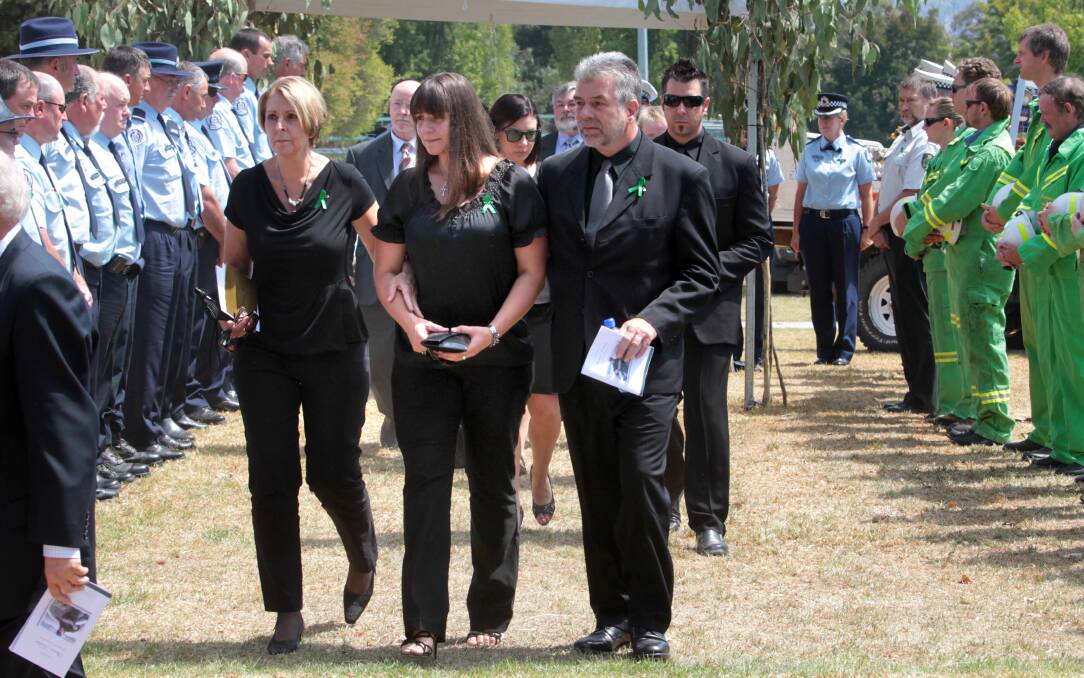 Emergency service personnel form a guard of honour at a memorial service for Steven Kadar as his partner Leah Edwards leaves the hall with her parents Petra and Ross Edwards, after the service. Picture: PETER MERKESTEYN