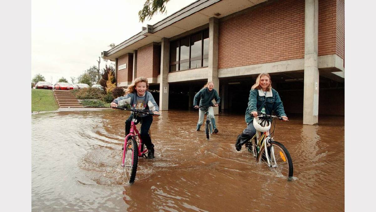 Candice Lee, 10, Krystal Lee, 10, and Deanne Young play in the floodwaters outside the council chambers. Picture: PETER MERKESTEYN
