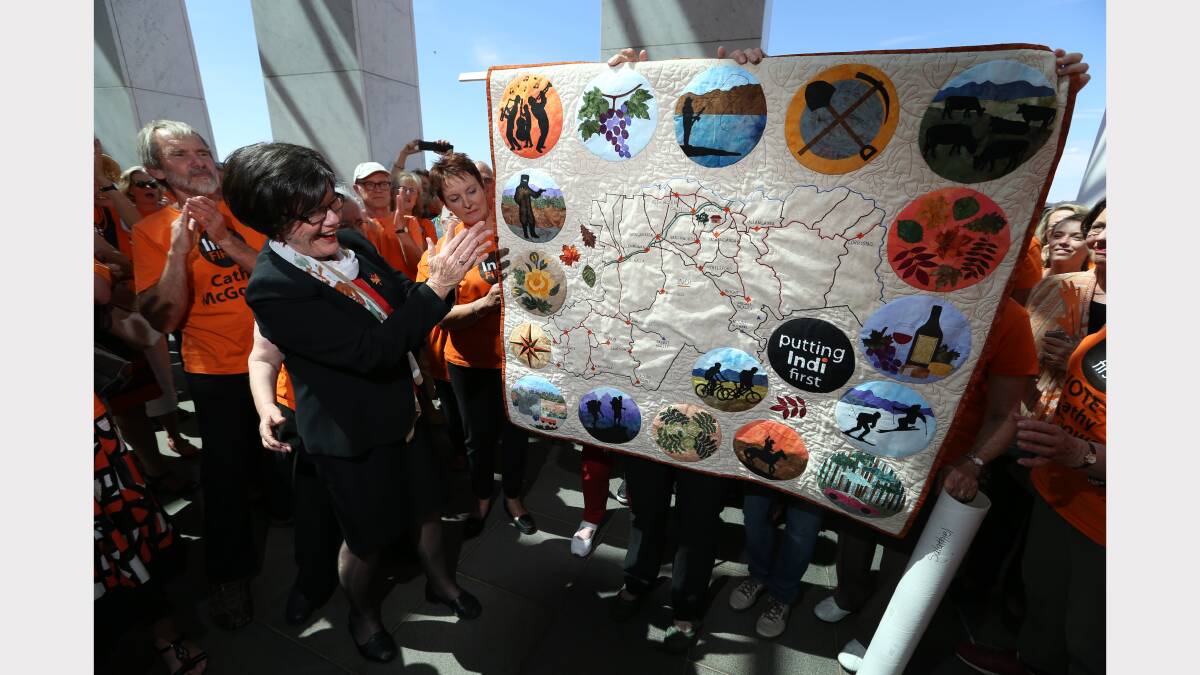 Member for Indi Cathy McGowan is presented with a quilt, handmade by a group of her supporters outside Parliament House in Canberra. 