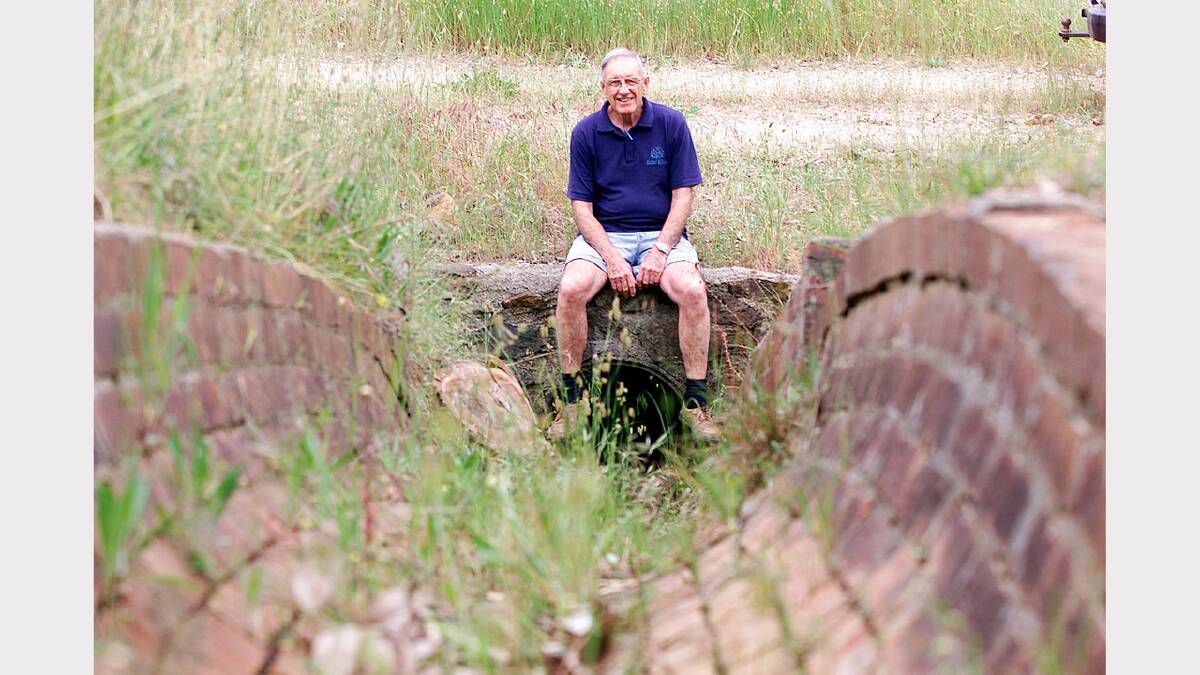 John Hillier shows a brick barrel race used for drainage at the Ebden station, built in 1888. The barrel sits on the Sandy Creek Rail Trail.  (2001)