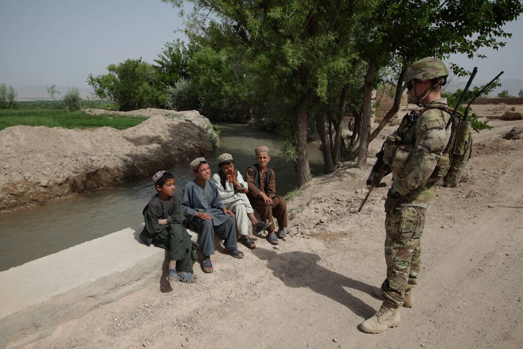 An Australian soldier from the Provincial Reconstruction Team (PRT), meets with Afghan children, during an operation to inspect a new road in the Oruzgan province, in Afghanistan, on 22 April 2013. Photo: Alex Ellinghausen
