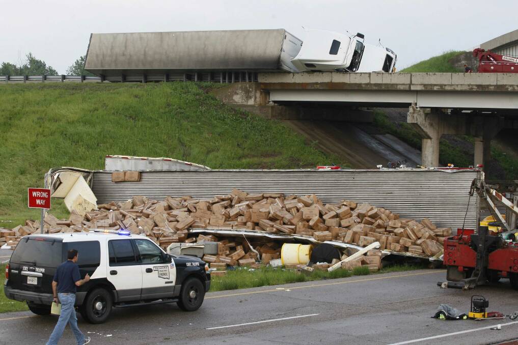A semi-tractor trailer (top) rests on its side against the guard rails on Interstate 40 as another trailer lies broken open on the road below after falling from I-40, following a tornado strike near Highway 177 north of Shawnee, Oklahoma. Photo: REUTERS