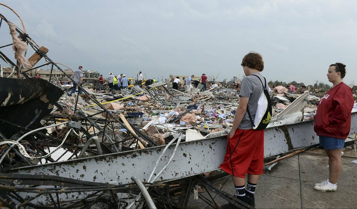 People watch as rescuers search through a convenience store that was destroyed after a tornado struck Moore, Oklahoma, May 20, 2013. Photo: REUTERS/Gene Blevins