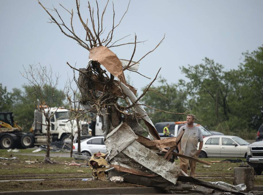 A man looks at metal debris twisted around a tree along a street, after a tornado struck Moore, Oklahoma, May 20, 2013. Photo: REUTERS/Gene Blevins
