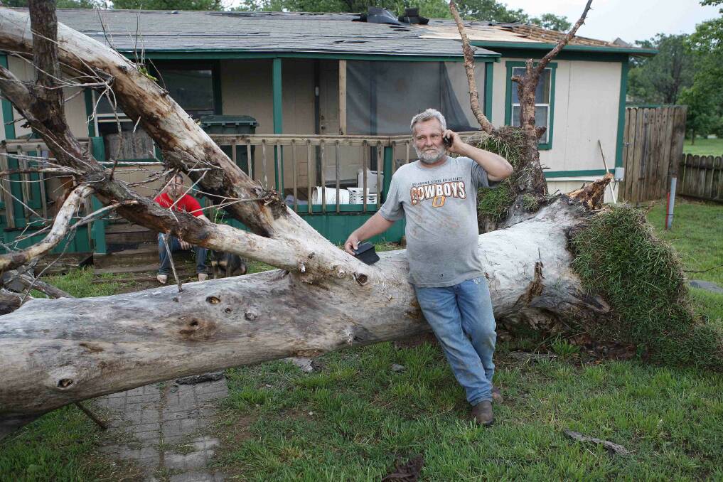 Allen Cook talks on his cell phone as he stands next to a downed tree which missed falling on a home in a mobile home park, where several other homes were destroyed by a tornado west of Shawnee, Oklahoma. Photo: REUTERS