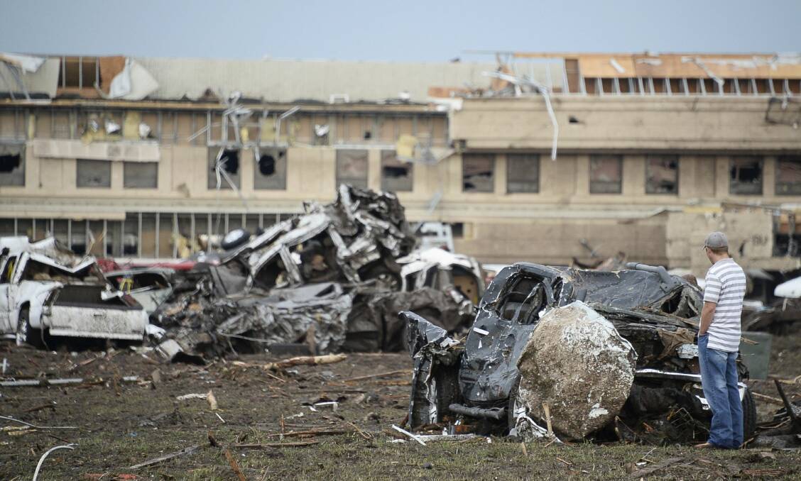 A man looks at a boulder that hit a car after a tornado struck Moore, Oklahoma, May 20, 2013. Photo: REUTERS/Gene Blevins