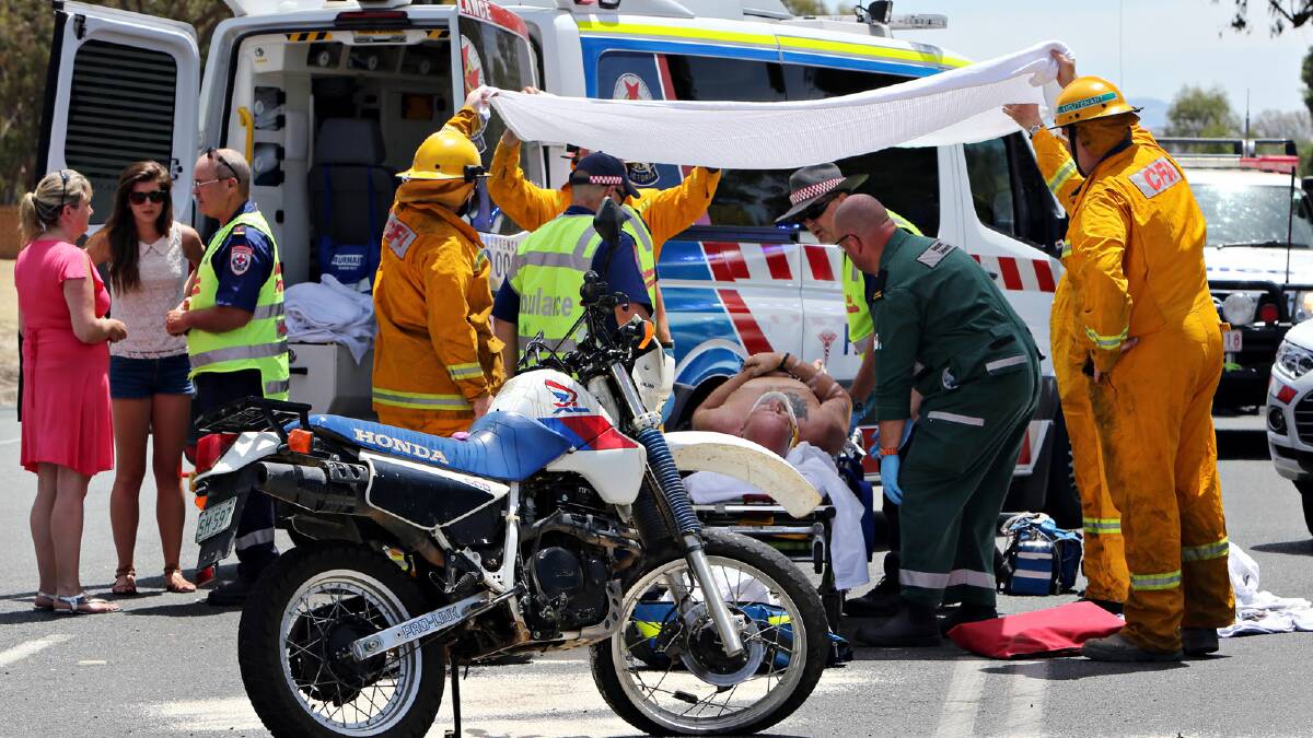 Alyse Burns is helped by a paramedic and her mother, Leeane, to treat the windscreen glass embedded in her legs. The learner driver hit a motorcyclist after he failed to give way. The rider was taken to hospital by ambulance. Picture: KYLIE ESLER