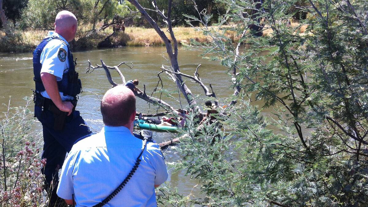 David Hawkins took this picture of police looking on as the woman was assisted after her canoe overturned on the Murray River yesterday afternoon.